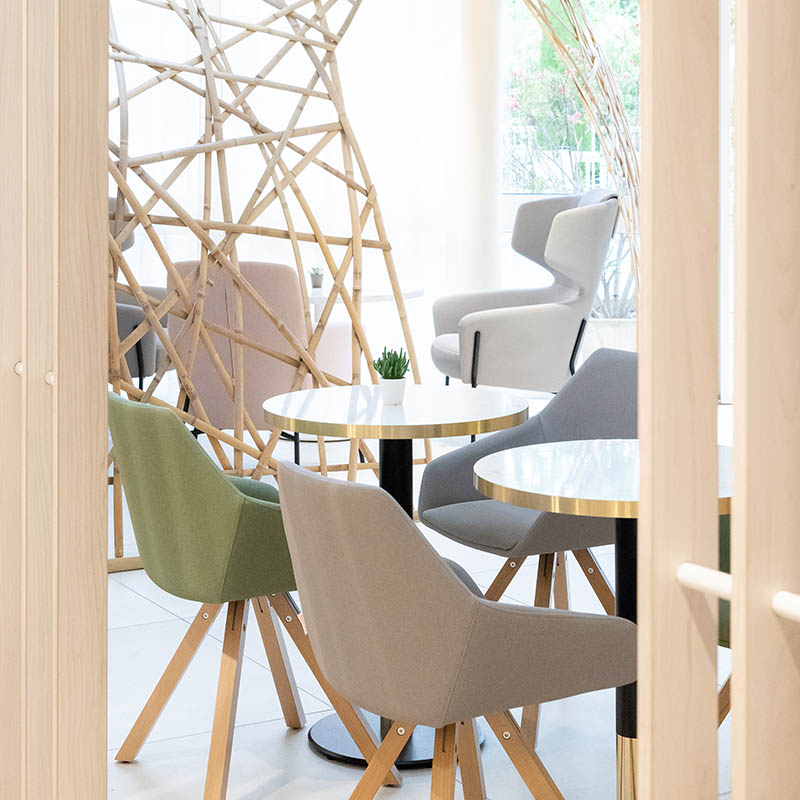 Photographe hôtel Marseille : espace détente design, chaises pastel et tables marbre, shooting déco pro en PACA.