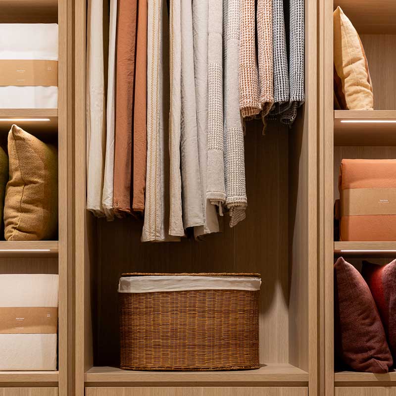 Photographe magasin Marseille : étagères bois boutique décoration, linge de maison, coussins et vannerie sous éclairage LED.