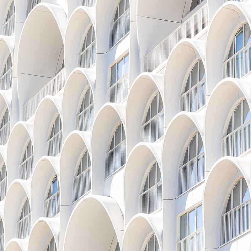Façade blanche de l'hôtel La Porte Bleue à Marseille, avec ses arches en béton sculpturales du quartier Euroméditerranée.