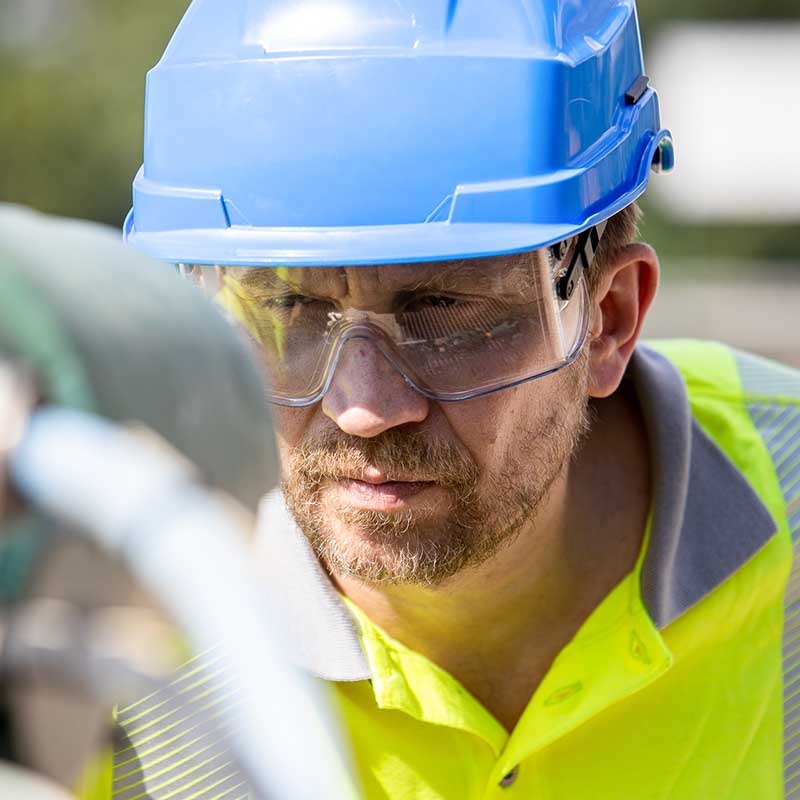 photo reportage corporate industriel marseille Photo corporate Marseille : portrait d'un technicien en casque bleu et lunettes de protection inspectant un site industriel.