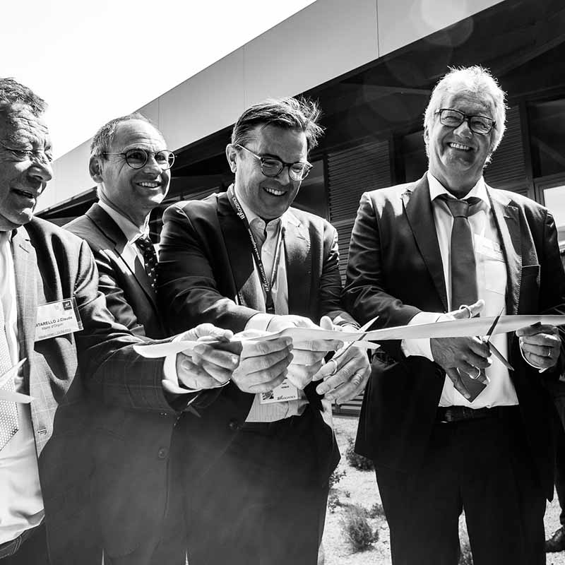 photo reportage evenement entreprise marseille Photo reportage Marseille : quatre hommes en costume souriants lors de la découpe d'un ruban inaugural pour une entreprise.