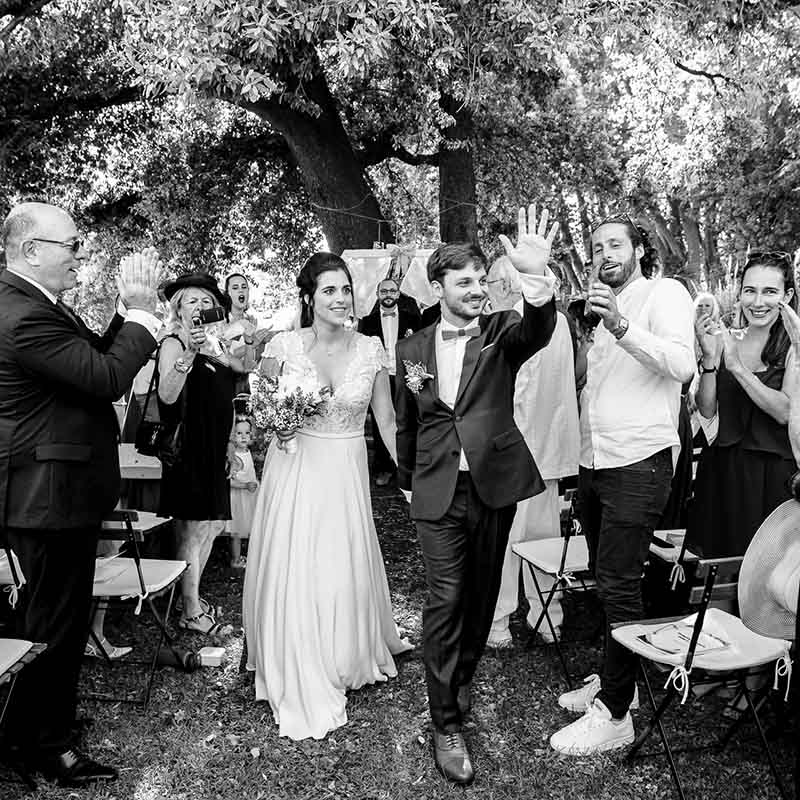 photographe cérémonie mariage marseille provence Mariés souriants saluant leurs invités sous les applaudissements lors d'une cérémonie de mariage en extérieur en Provence.