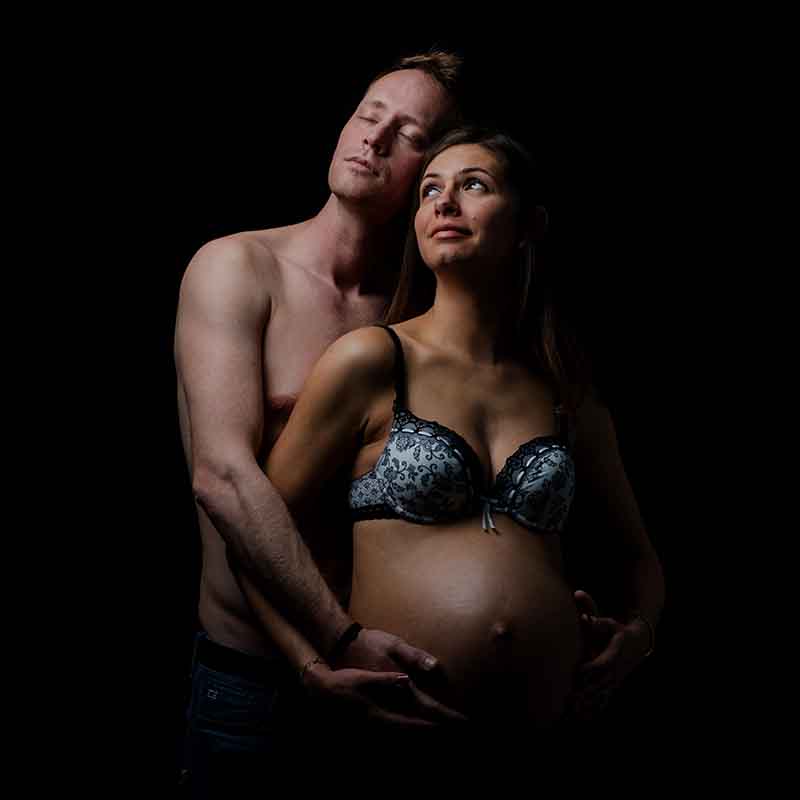 photographe photo grossesse Marseille Photographe grossesse Marseille : couple en studio, femme enceinte et mari posant sur fond noir en PACA.