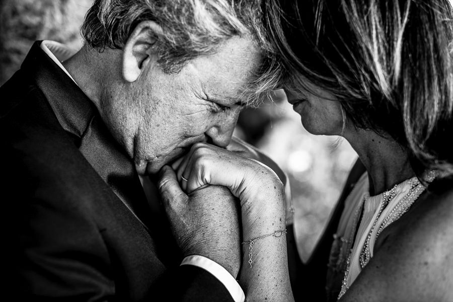 Portrait en noir et blanc d'un père de mariée ému embrassant les mains de sa fille en pleurant lors d'un mariage à Marseille.