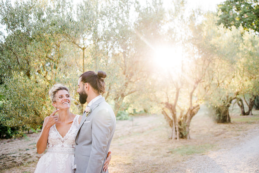 Portrait d'un couple de mariés complices dans une oliveraie en Provence, éclairé par une lumière dorée naturelle près de Marseille.