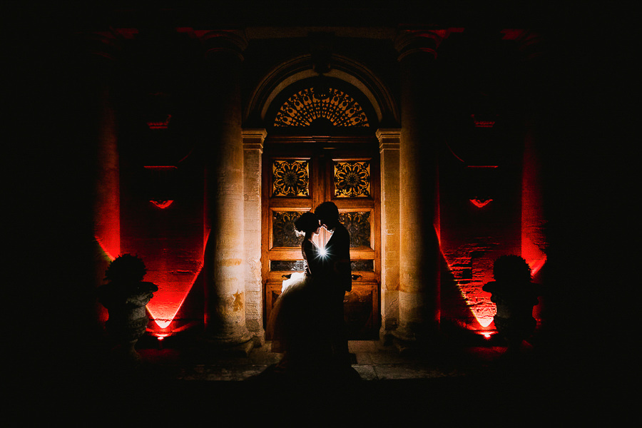 Silhouette d'un couple de mariés en contre-jour devant une porte ancienne illuminée à Marseille lors d'une séance photo nocturne.